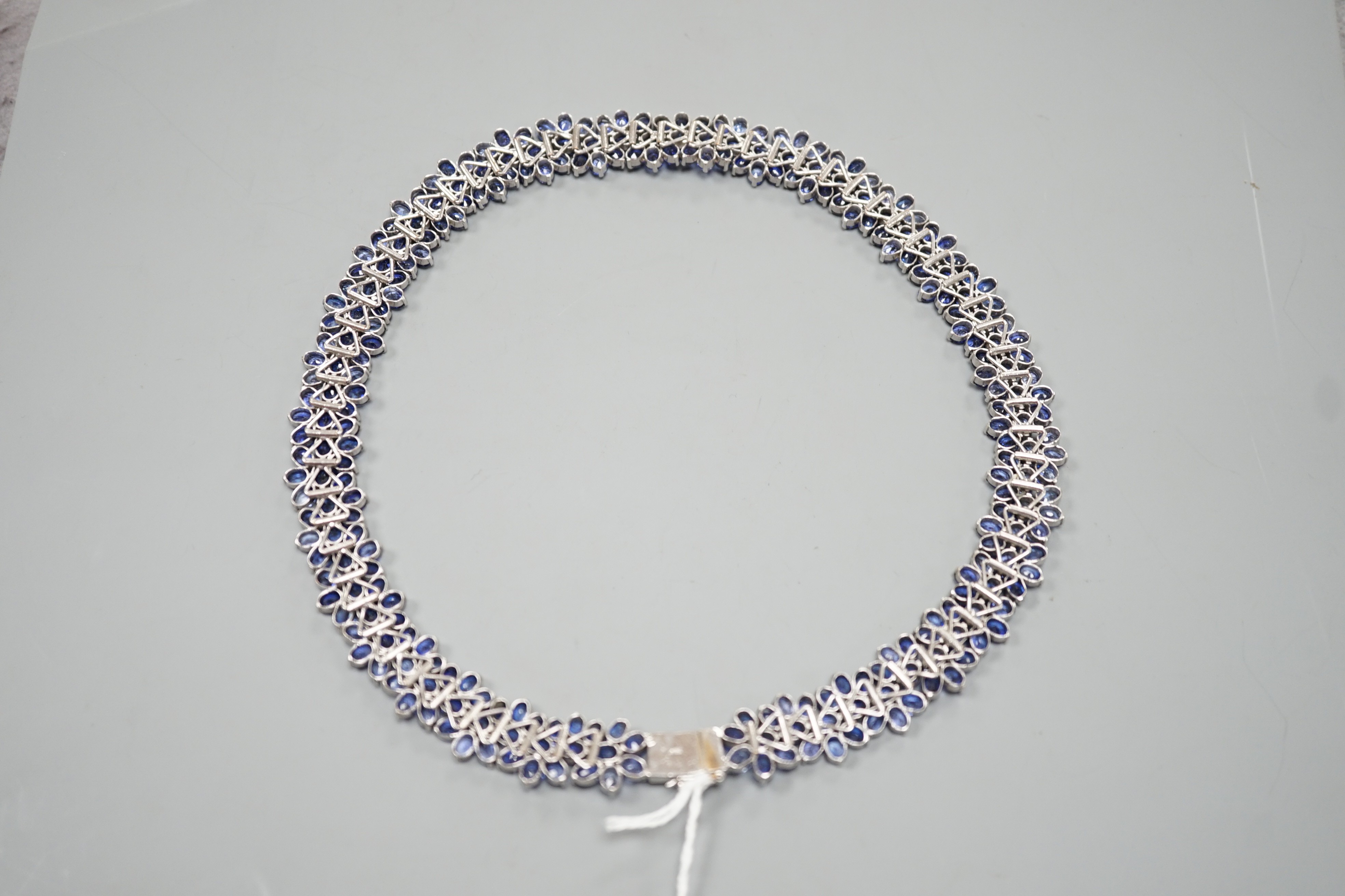 A continental base metal and synthetic sapphire? flower head cluster set necklace, approximately 39cm.